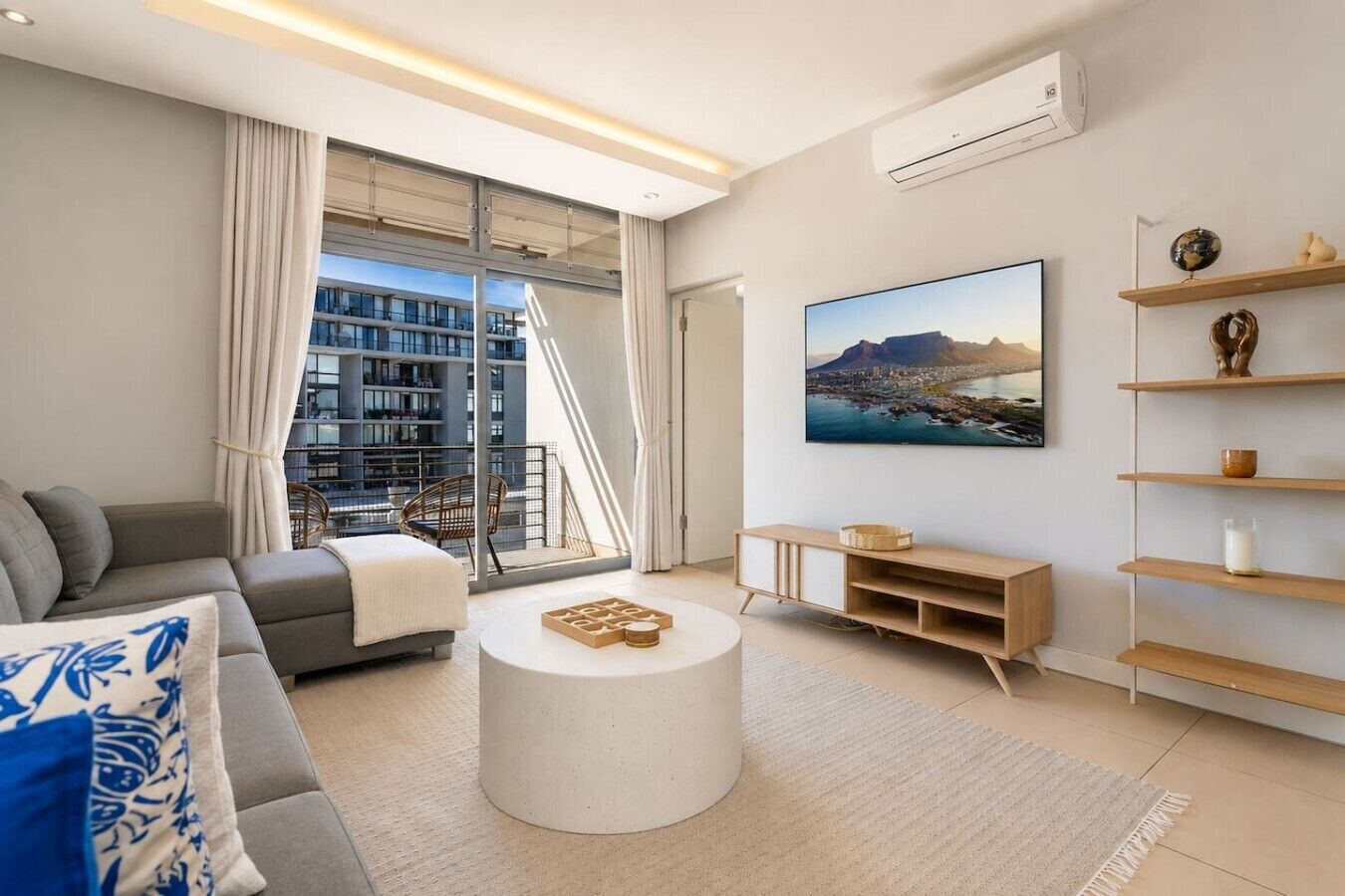 A modern living room with a sofa, coffee table, and a large window overlooking a cityscape.