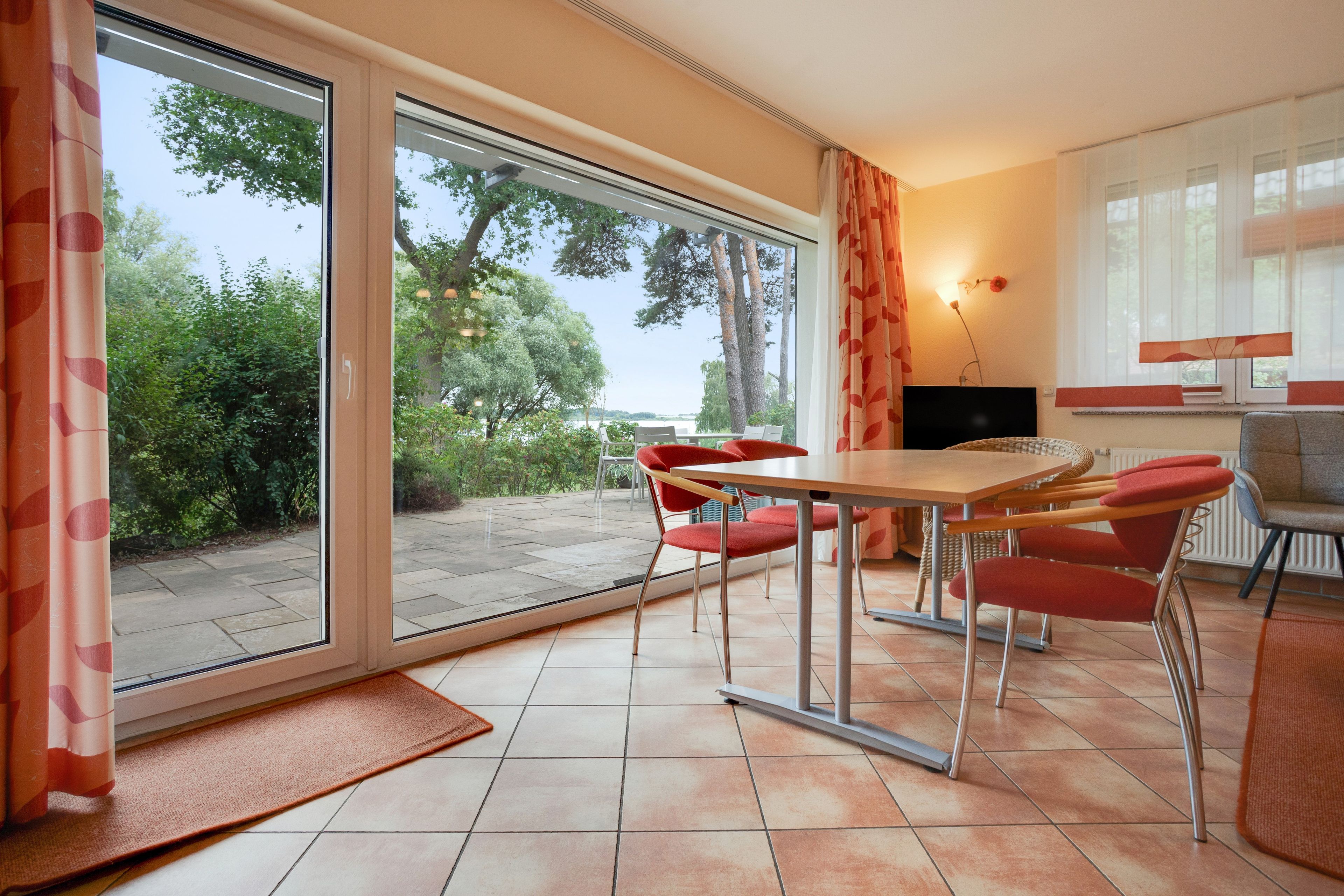 Un comedor con mesa y sillas, televisor y vistas al exterior.