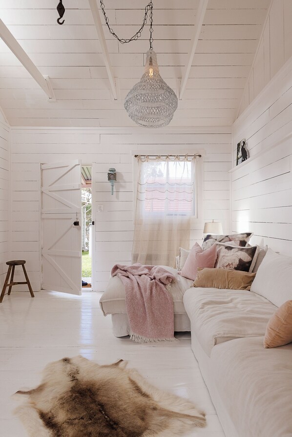 Een kamer met een bed, een hanglamp, een raam met gordijnen en een deur die naar buiten leidt.