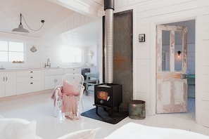 A modern kitchen with white cabinetry, a built-in stove, and a rustic door.
