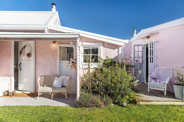 A house with a porch, a wicker chair, and a potted plant.