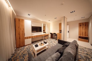 Uma sala de estar moderna com um sofá, uma mesa de centro e uma TV fixada na parede.