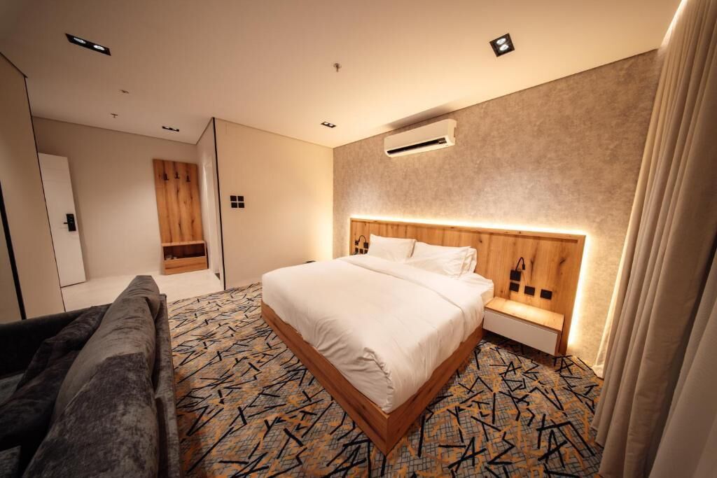 Una habitación de hotel con cama, mesita de noche y sofá.