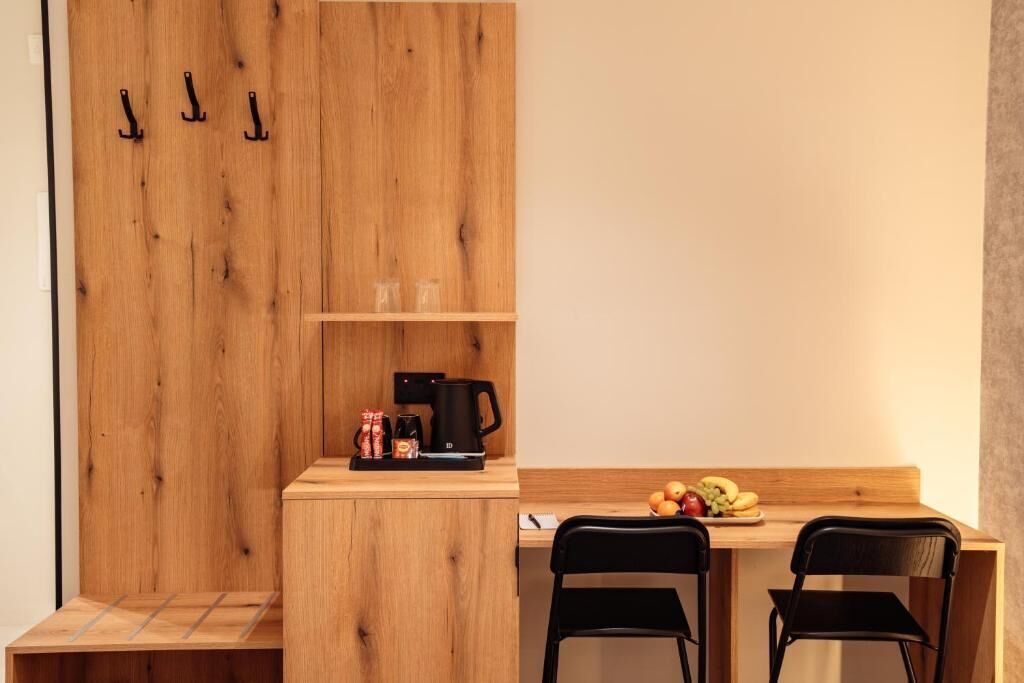 Un comedor de madera con una cafetera, un frutero y dos sillas.
