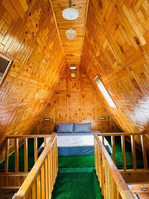 An attic bedroom with wooden walls, a green carpet, a bed, and a wooden railing. - Latos Chapter Sajwar (Banjar)
