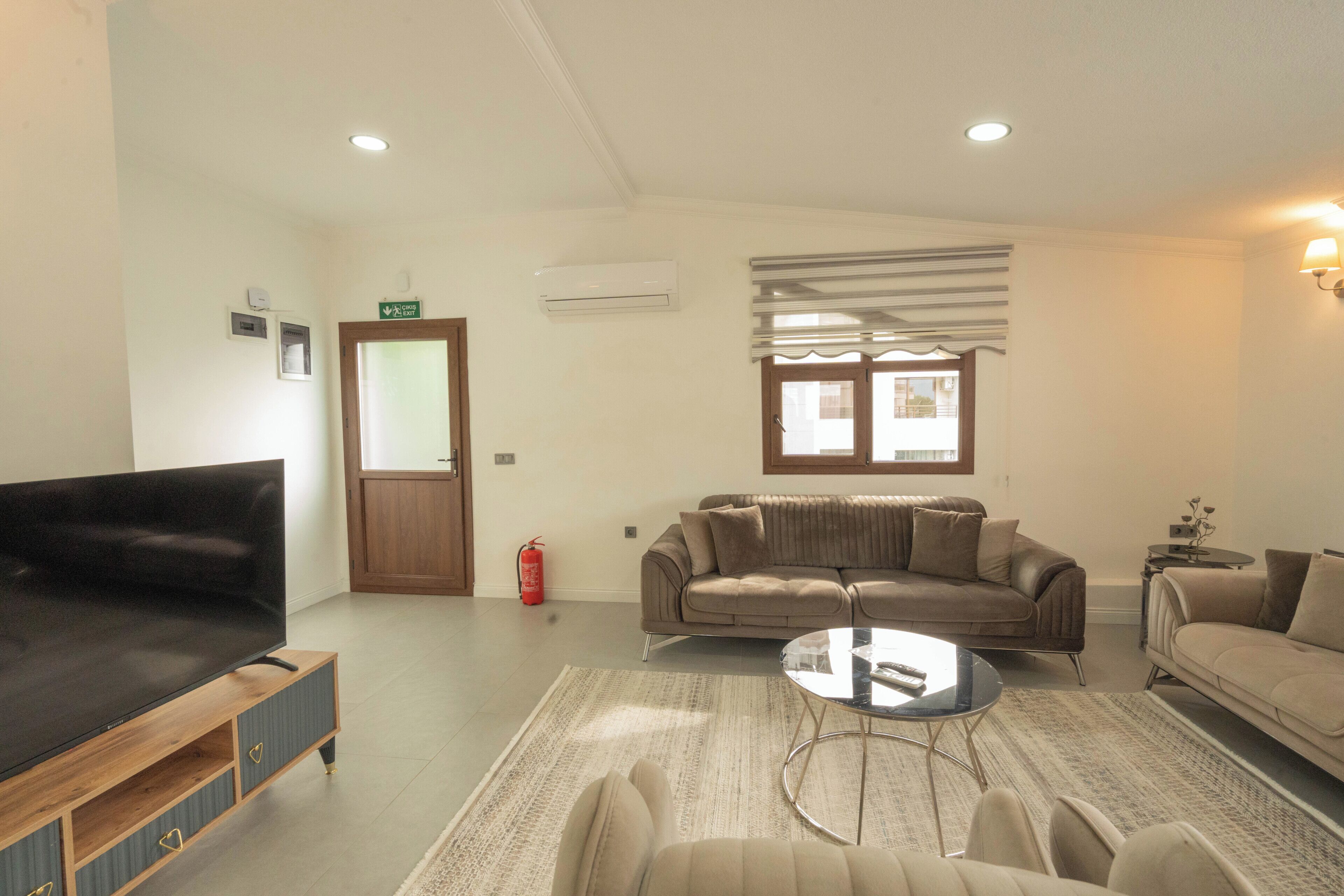A living room with a flat-screen TV, a sofa, a loveseat, and a coffee table.
