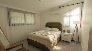 Quarto com cama, mesas de cabeceira, uma cadeira e abajur.