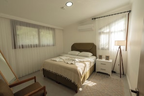 Een slaapkamer met een bed, nachtkastjes, een stoel en een vloerlamp.