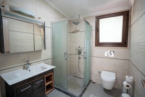 Een moderne badkamer met een douchecabine van glas, een wit wastafelmeubel en een toilet.