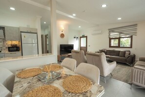 A modern living space with a dining area, kitchen, and seating area. - Beach Suite L Penthouse İcmeler (Muğla)