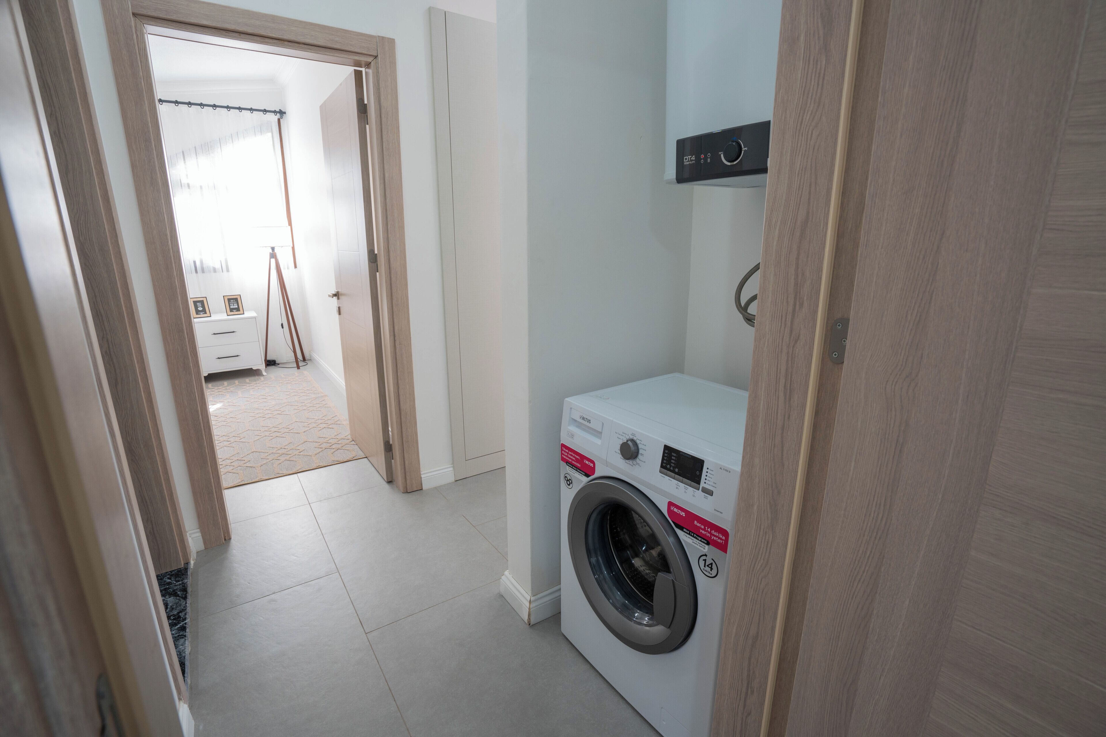 A laundry room with a washing machine, a drying rack, and a small cabinet.