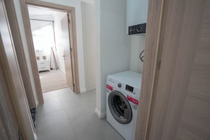 A laundry room with a washing machine, a drying rack, and a small cabinet. - Beach Suite L Penthouse İcmeler (Muğla)