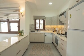 A compact kitchen with a dishwasher, stove, and refrigerator. - Beach Suite L Penthouse İcmeler (Muğla)