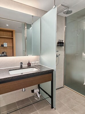 Een moderne badkamer met een wastafelmeubel met dubbele wastafel, een douchecabine van glas en een spiegel met een geëtst paneel.