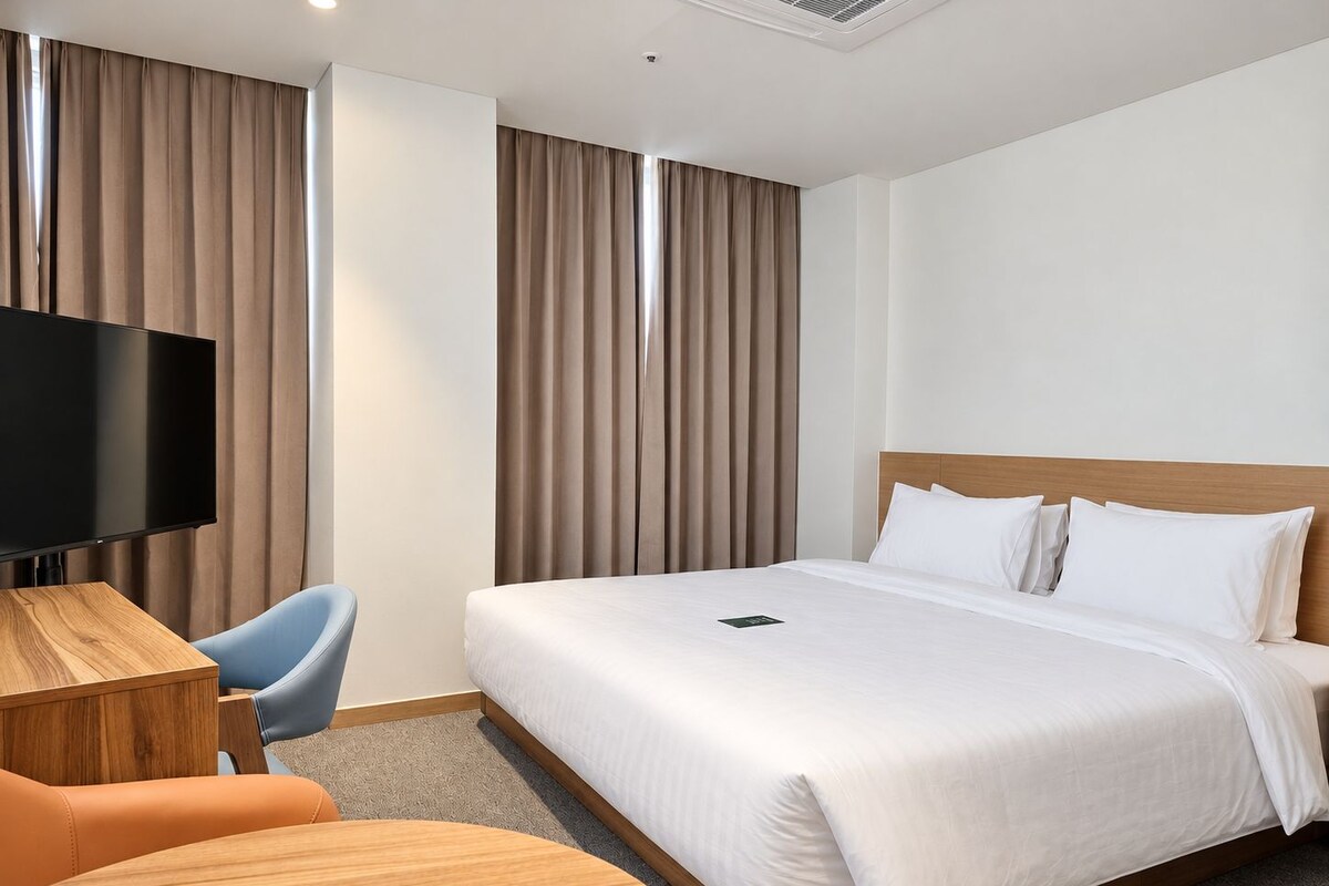 Een hotelkamer met een bed, een flatscreen televisie, een bureau en een stoel.