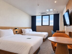 Een hotelkamer met twee bedden, een televisie, een bureau en een raam met gordijnen.
