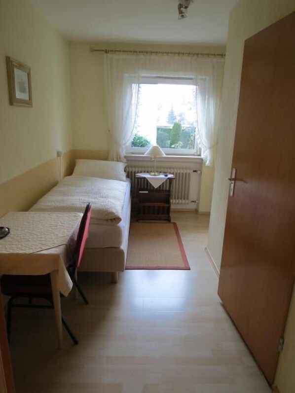 Un dormitorio con cama, una mesa y un ventanal con cortinas.