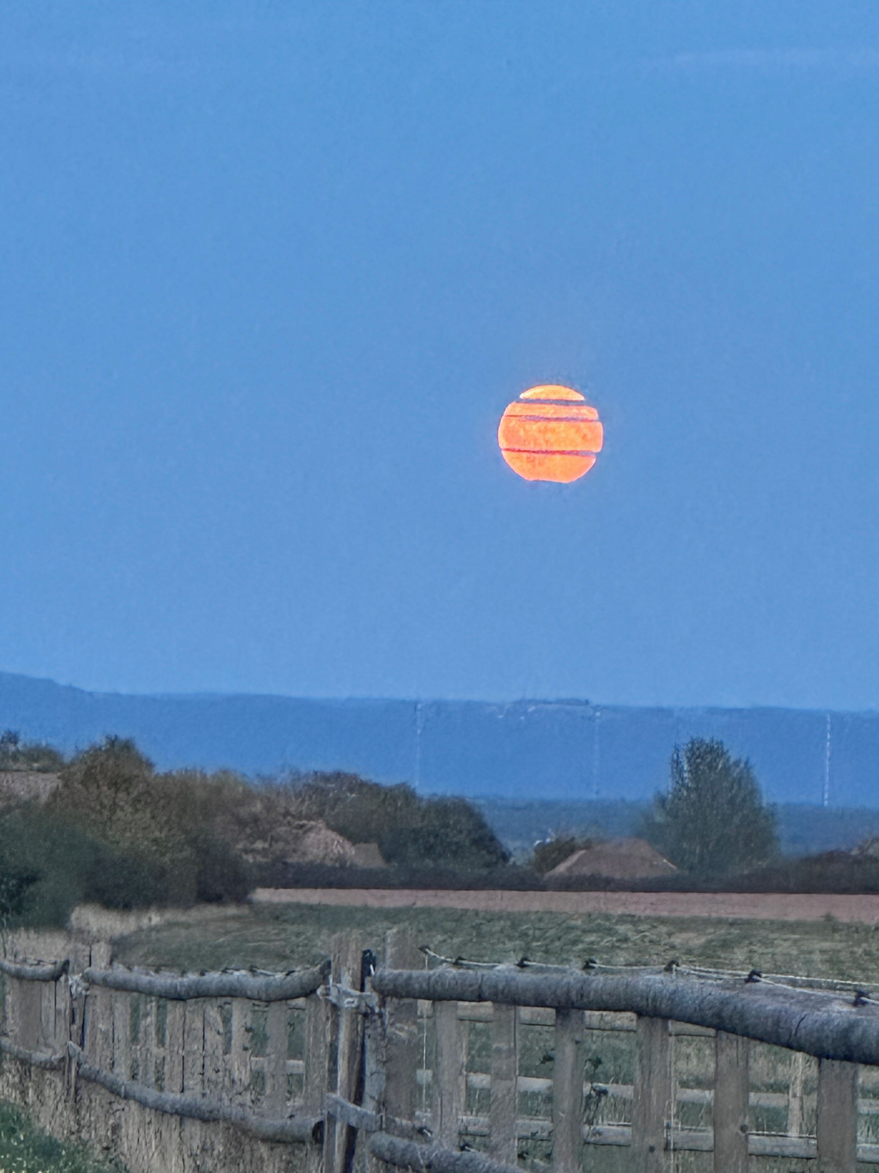A clear sky with a large orange sun.