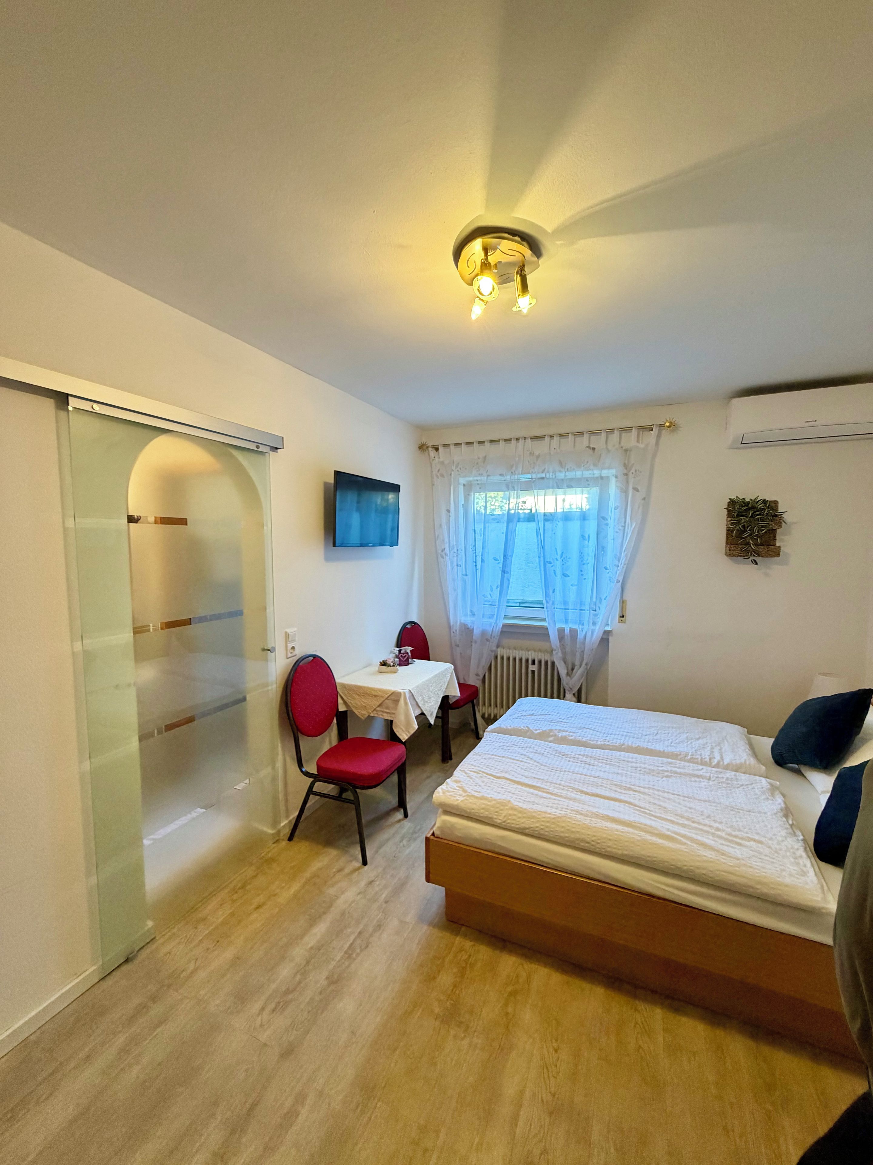 Ein Schlafzimmer mit einem Bett, einem Schreibtisch, einem Stuhl und einem Fernseher.
