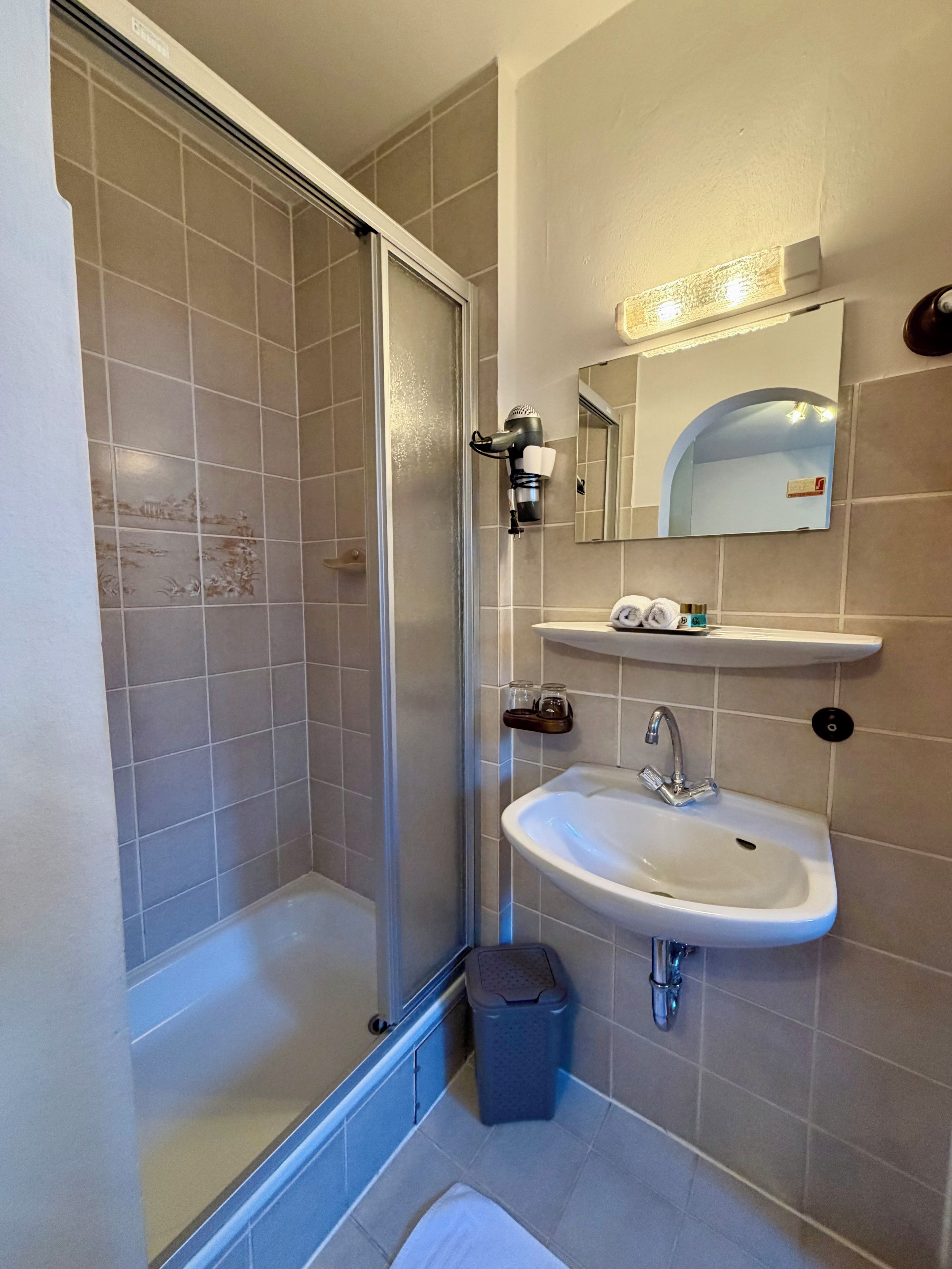 Ein Badezimmer mit Dusche, Waschbecken, Spiegel und Handtuchhalter.