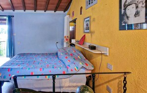 A bedroom with a bed, a shelf with items, and a window with curtains. - 1 bedroom cozy home in Levigliani (Levigliani)