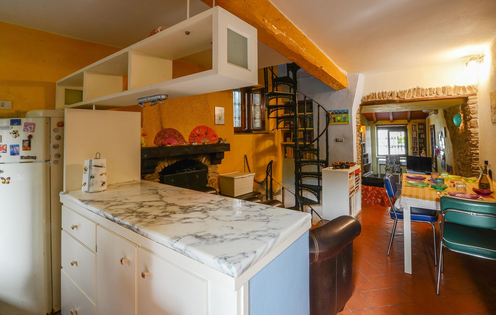 Uma cozinha com bancada de mármore, lareira e estante de livros.