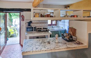 A kitchen with a marble countertop, a microwave, a stove, and a sink. - 1 bedroom cozy home in Levigliani (Levigliani)