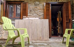 A rustic stone building with wooden shutters, a small wooden table, and two green plastic chairs. - 1 bedroom cozy home in Levigliani (Levigliani)