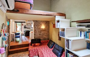 A cozy living area with a sofa, a bookshelf, and a kitchen in the background. - 1 bedroom cozy home in Levigliani (Levigliani)