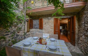A stone building with a dining area set up outside. - 1 bedroom cozy home in Levigliani (Levigliani)
