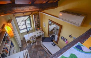 A room with a white desk, a chair, a bookshelf, a radiator, a window, and an air conditioning unit. - 1 bedroom cozy home in Levigliani (Levigliani)