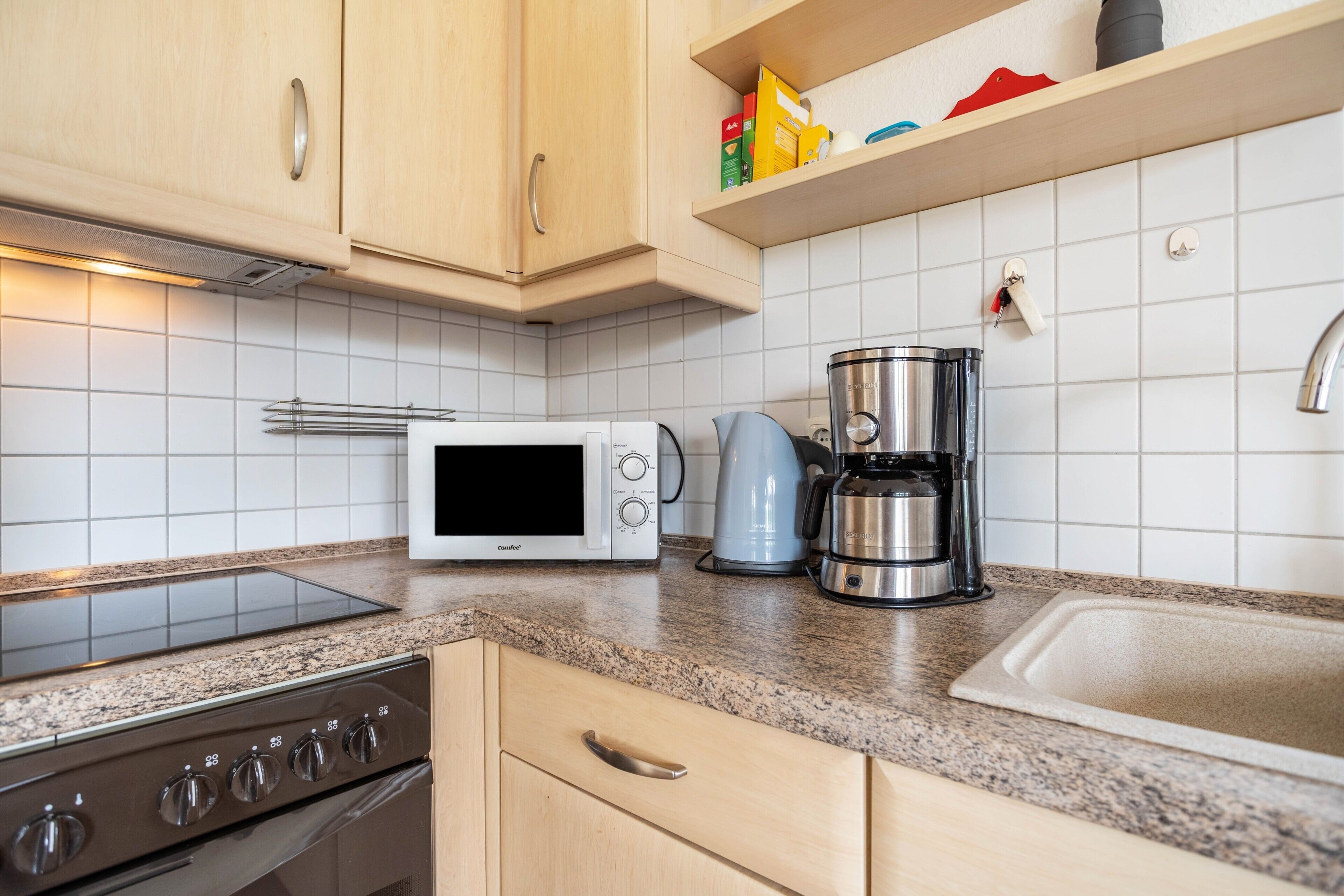 A kitchen with a microwave, coffee maker, and stove.