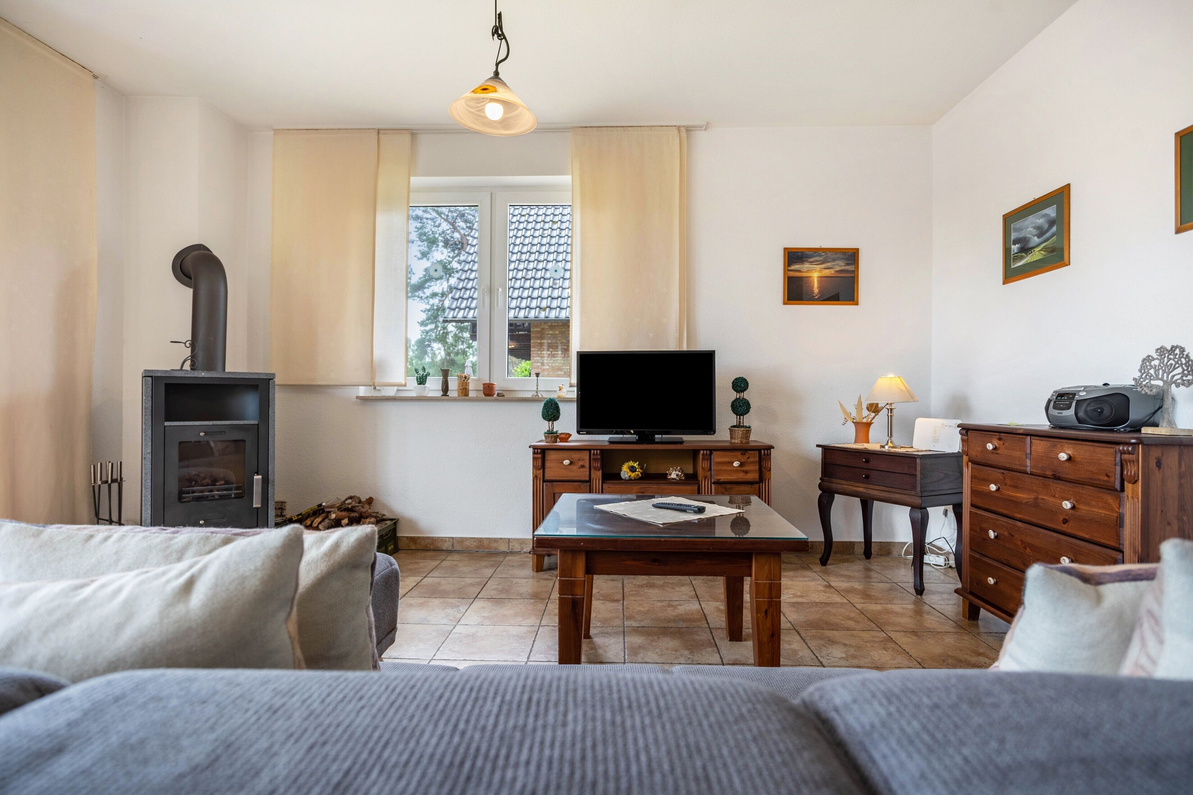 Ein Wohnzimmer mit einer Couch, einem Fernseher auf einem Holzschrank, einem Tisch mit einer Fernbedienung, einer Lampe und einem Kamin.