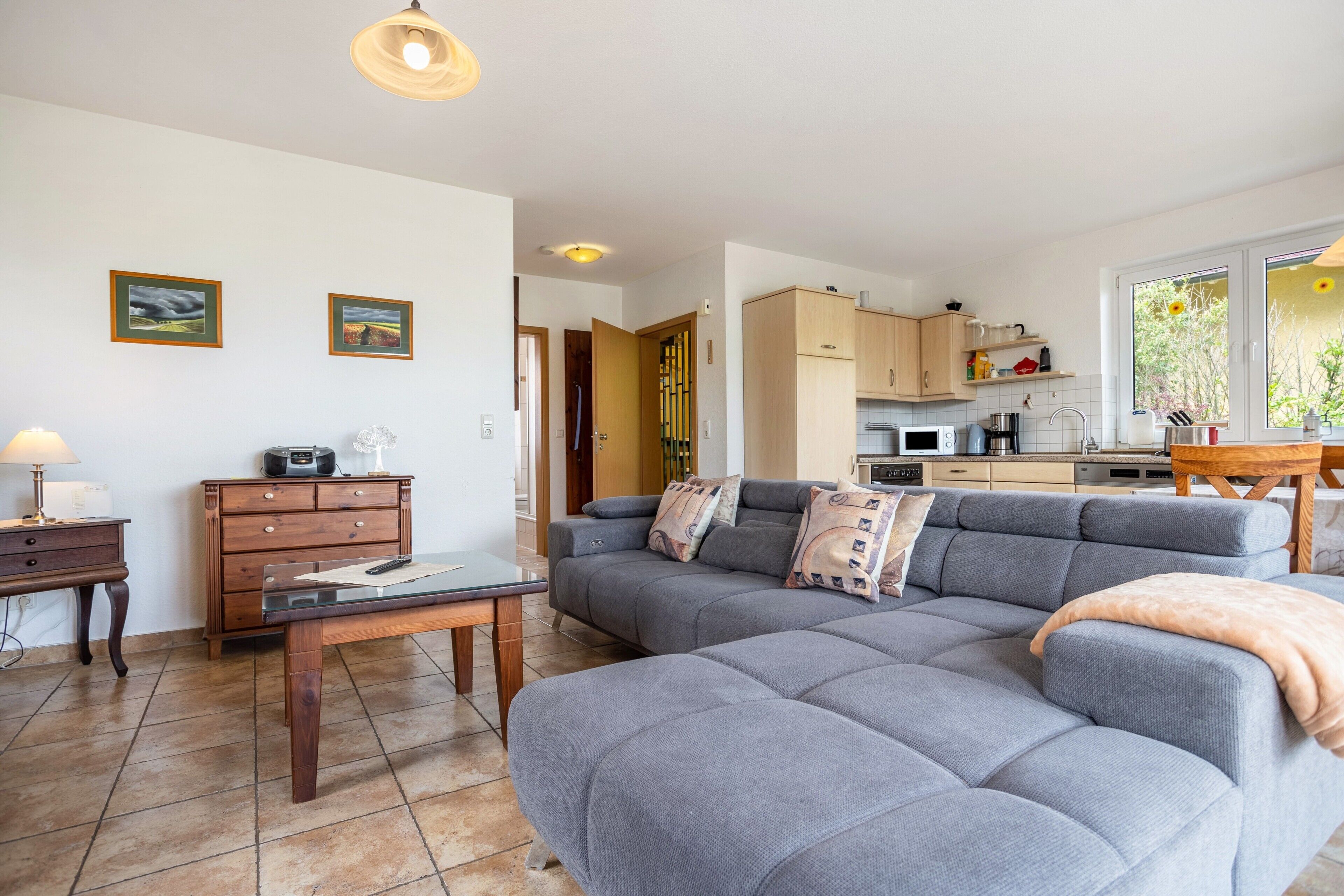 Een woonkamer met een grijze bank, een houten salontafel en een tv-meubel met een radio.