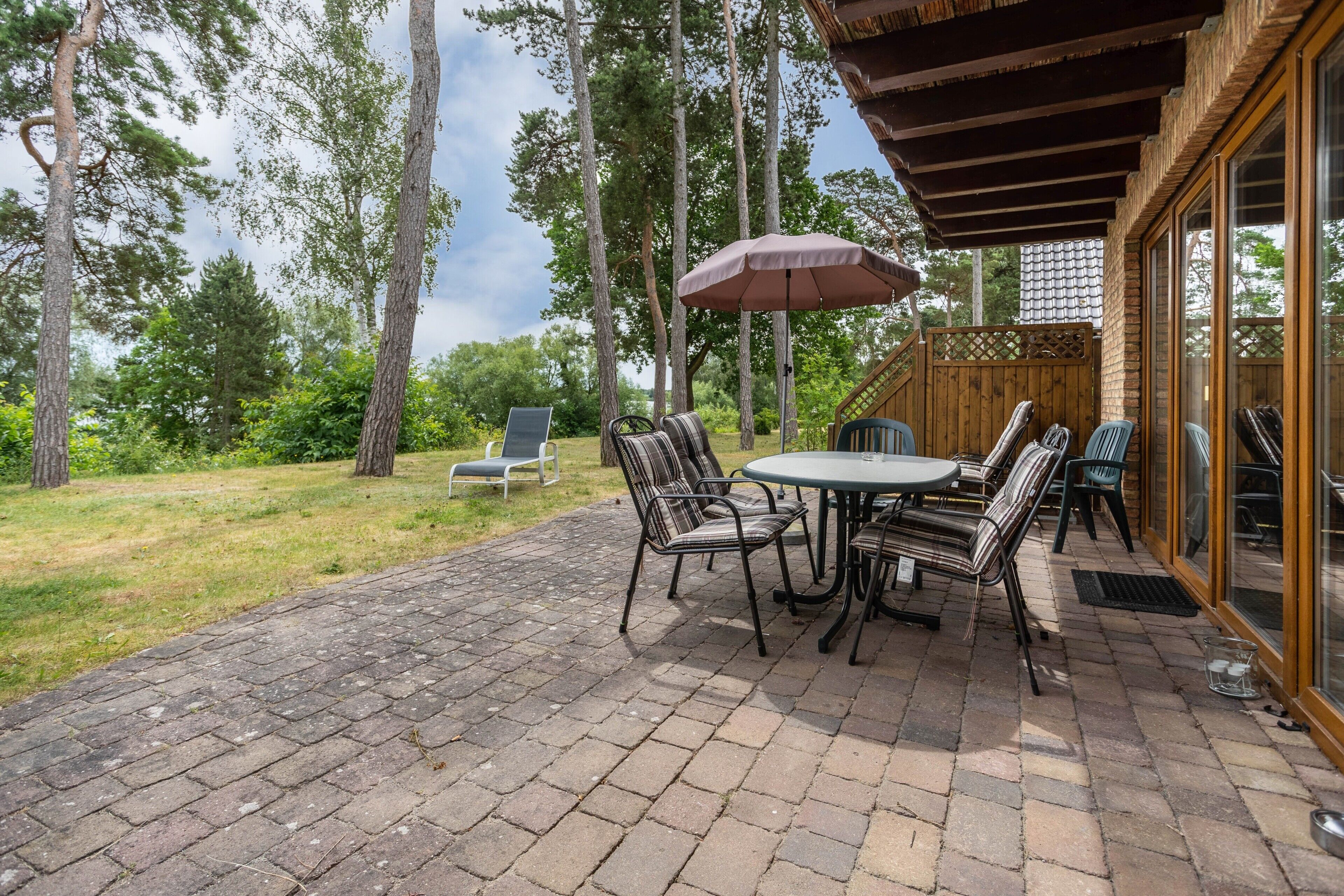 Eine Terrasse im Freien mit Pflasterboden, einem runden Tisch und sechs Stühlen.