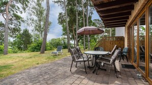 Eine Terrasse im Freien mit Pflasterboden, einem runden Tisch und sechs Stühlen.