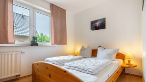 Ein ordentlich bezogenes Bett mit weißen Leinen, einem Holz-Kopfteil und einem Fenster mit Vorhängen.
