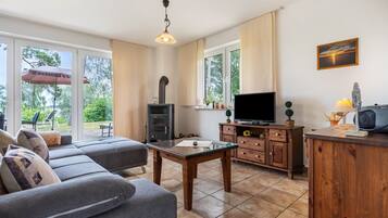 Una sala de estar moderna con un sofá, una mesa de centro de vidrio, un televisor y una chimenea.
