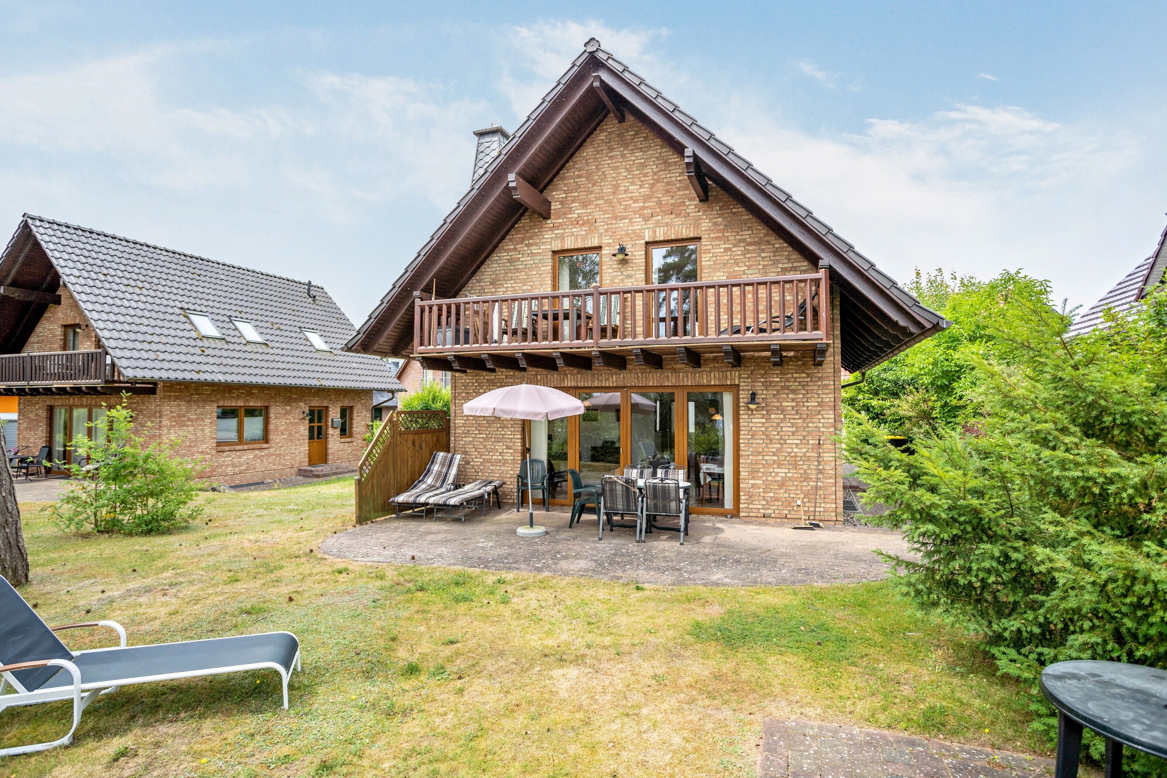 A two-story chalet with a balcony, outdoor seating, and a patio area.