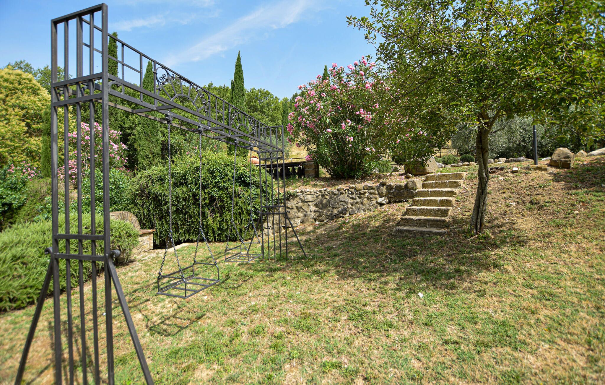 A stone staircase leading up to a wooden deck, surrounded by lush greenery and flowering plants.