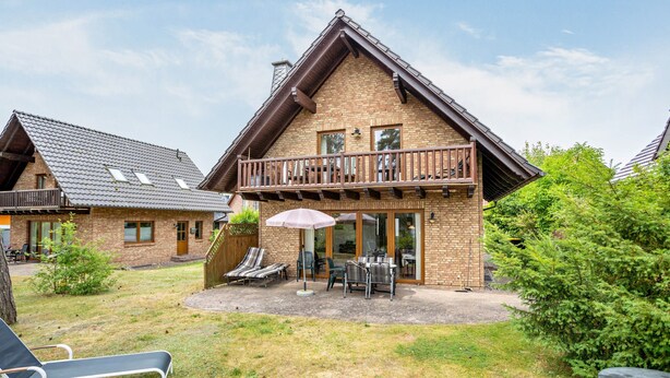 Eine zweistöckige Chalet mit Balkon, Sitzgelegenheit im Freien und einer Terrassenfläche.