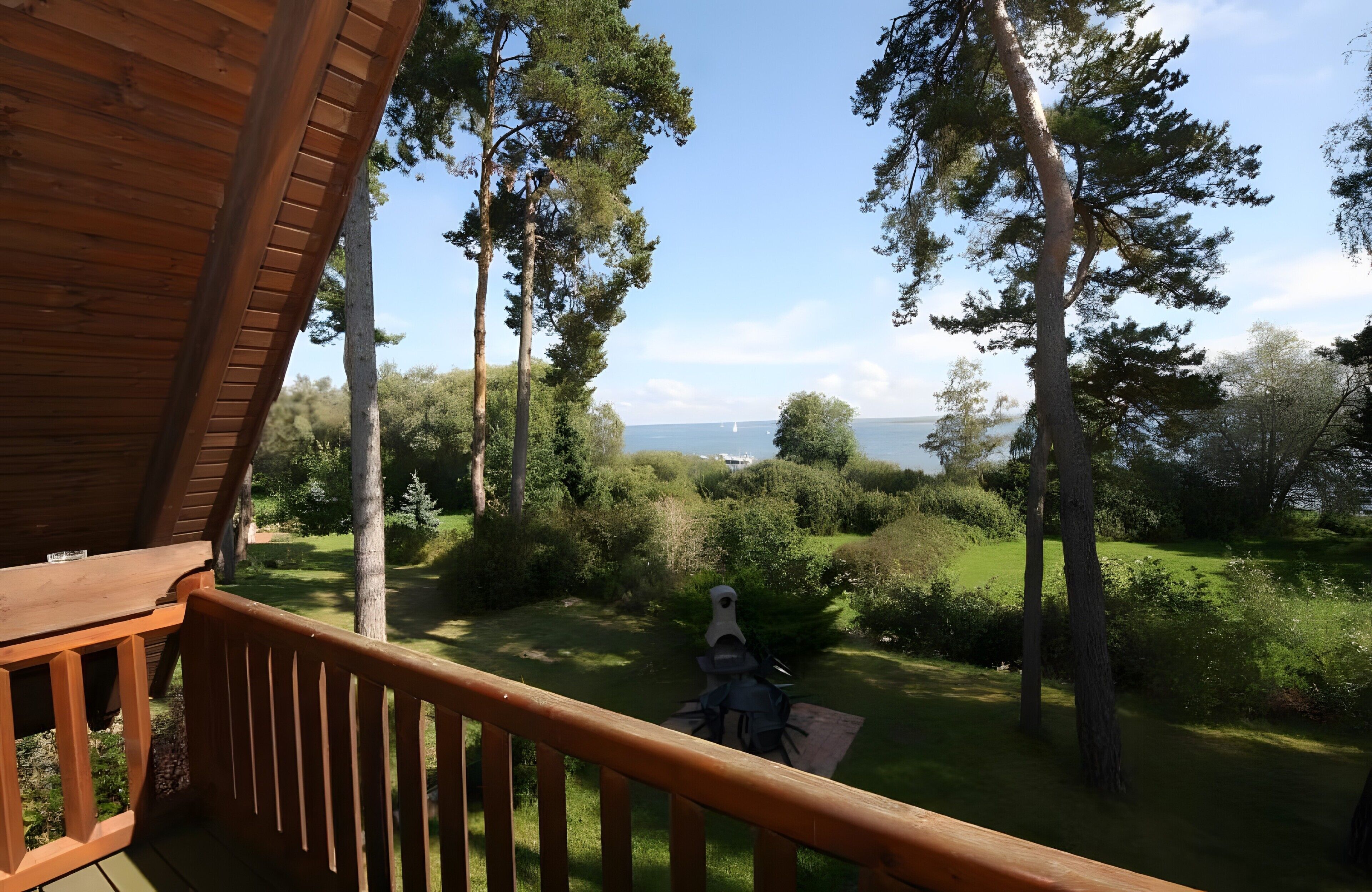 A wooden deck with a view of a grassy landscape and trees.