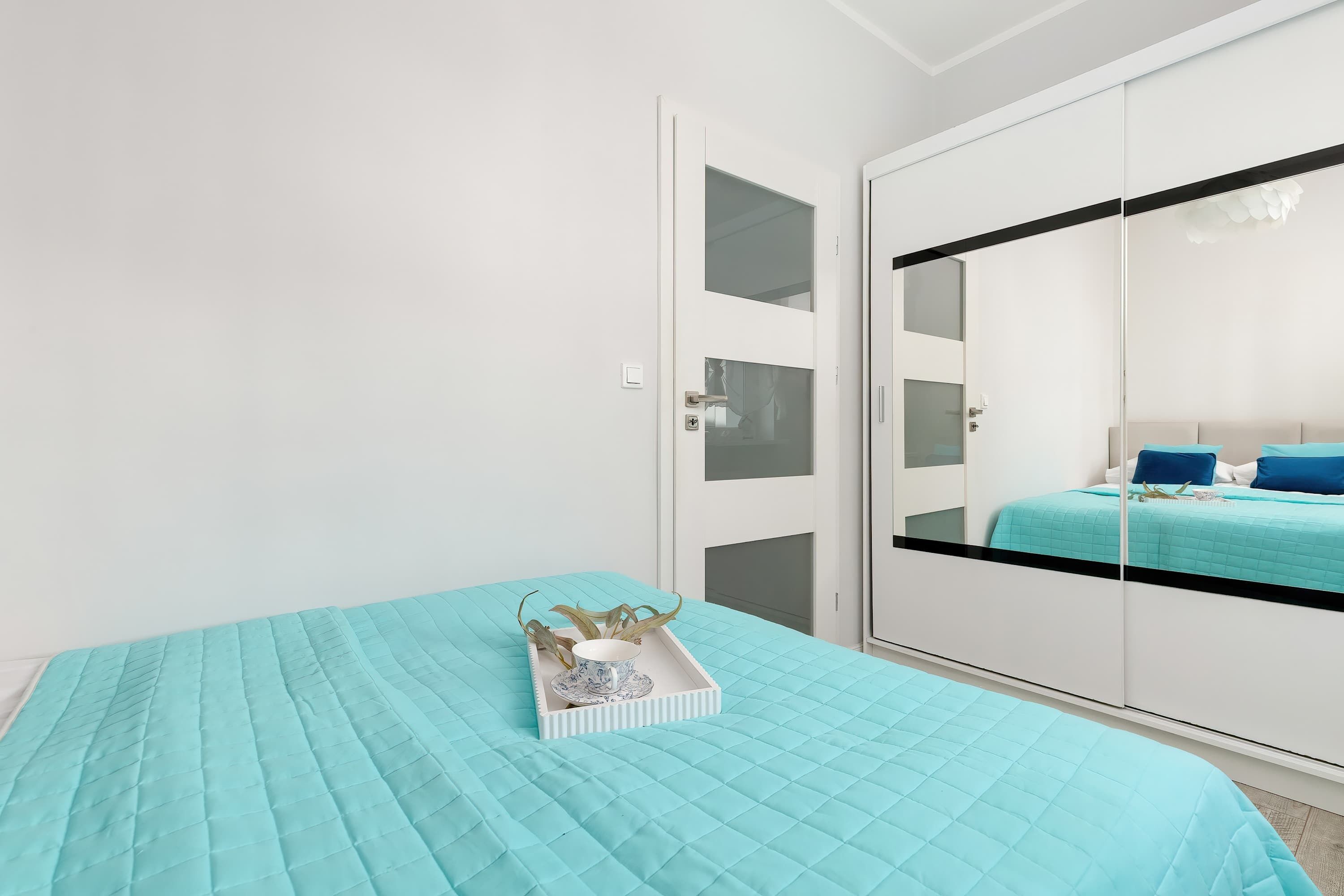 A bedroom with a bed, a wardrobe, and a bedside table with a tray.