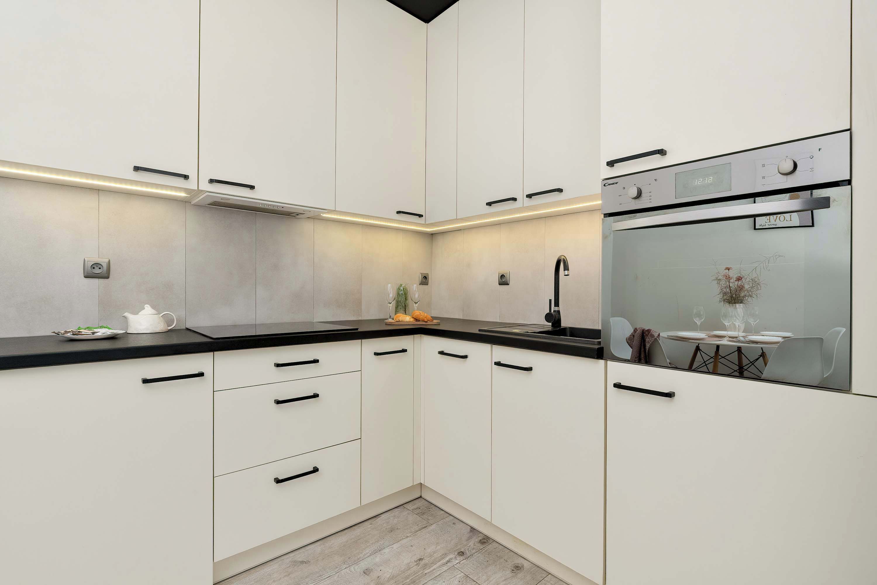 A modern kitchen with white cabinetry, a black countertop, and a built-in oven.