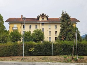 En byggnad med flera våningar, ett platt tak, balkonger och en central entré.