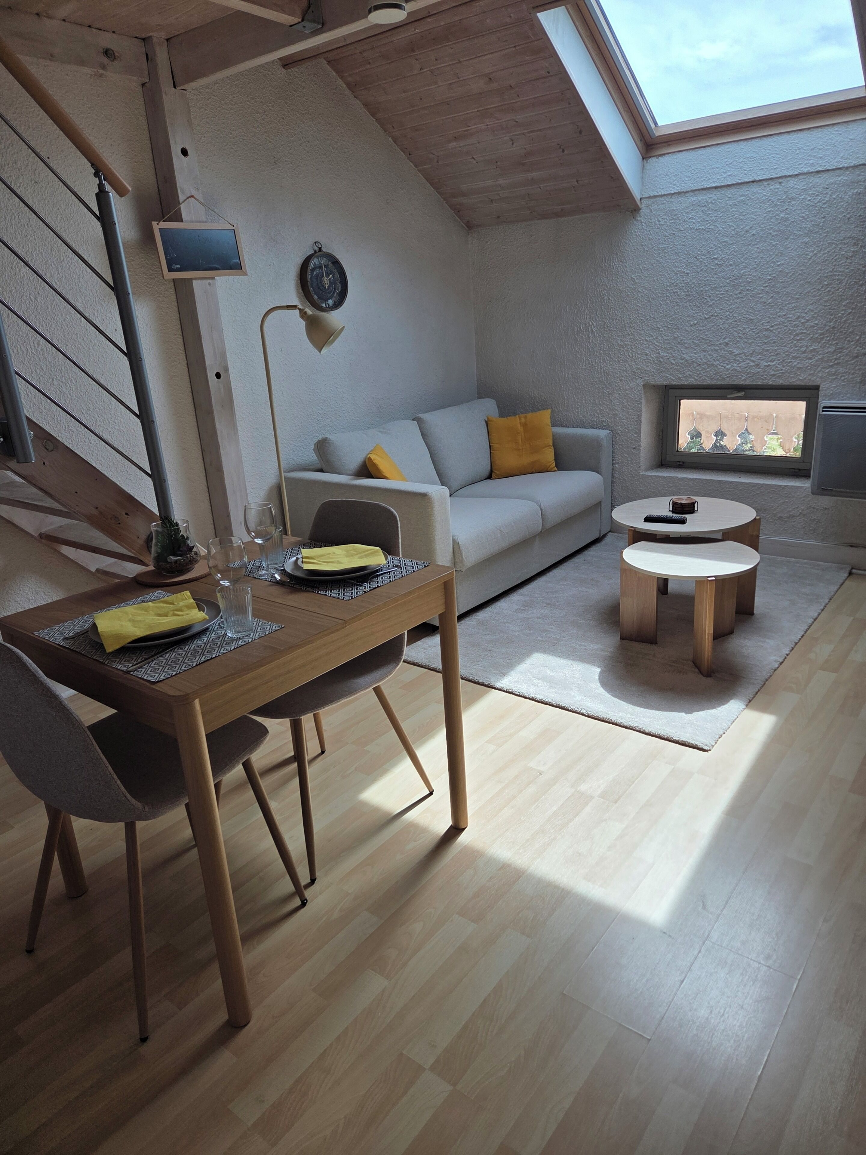 A loft-style living space with a dining area, a sofa, and a small table.