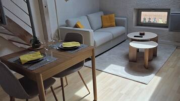 A loft-style living space with a dining area, a sofa, and a small table.