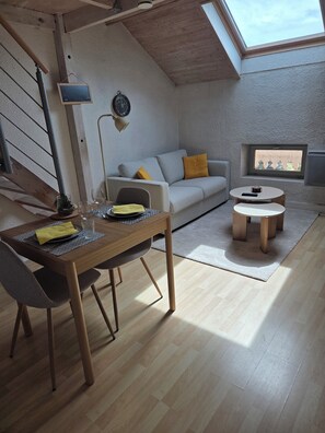 A loft-style living space with a dining area, a sofa, and a small table.