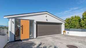Un garage moderne doté d’une porte coulissante, d’une porte de garage et d’une allée en béton.