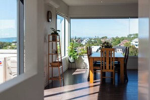 Un espace repas offrant une vue sur un quartier résidentiel et la mer.